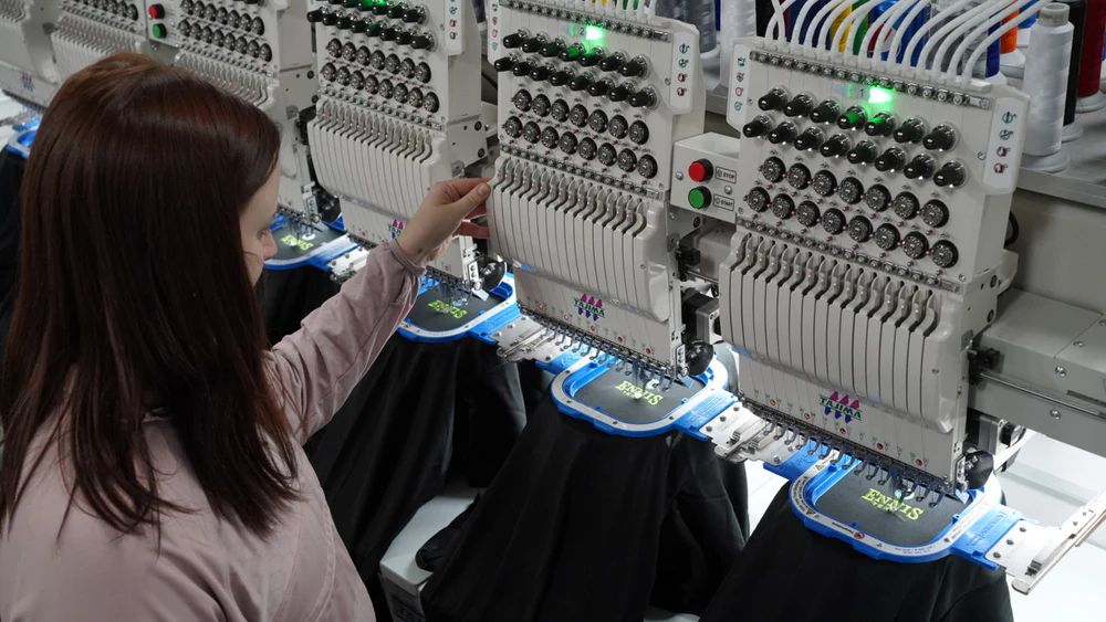 Custom embroidery machines producing branded apparel with precision stitching at PROMOXWEAR